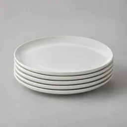 A centered stack of plain white ceramic serving plates photographed on a neutral light background.