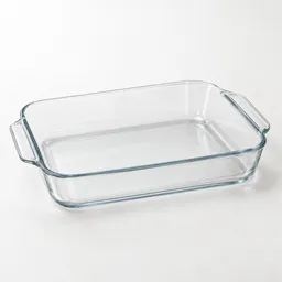 Centered clear glass 9-by-13-inch rectangular baking dish with rounded corners and side handles on a neutral light background.
