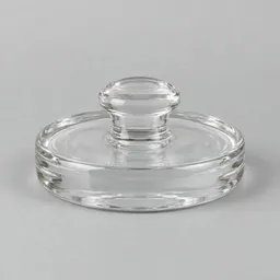 Centered clear glass fermentation weight with a rounded central grip on a neutral light background.
