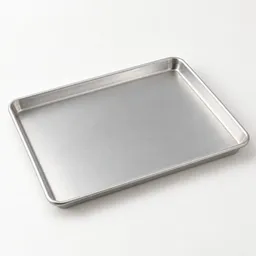 Centered unbranded 13-by-18-inch rimmed aluminum baking sheet photographed at a slight angle on a neutral light background.