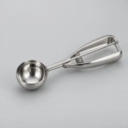 Centered stainless-steel cookie scoop photographed against a light neutral background.