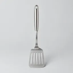A single stainless-steel slotted kitchen turner centered on a light neutral background.