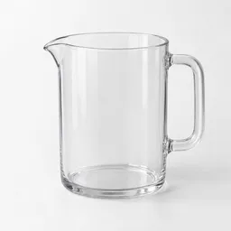 Clear measuring jug with a handle and pouring spout on a neutral light background.