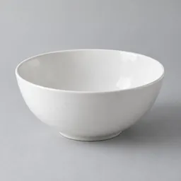 A single empty white ceramic salad bowl centered against a light neutral background.