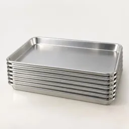 Centered stack of plain aluminum rimmed sheet pans on a light neutral background.