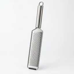 Centered fine-mesh stainless-steel grater photographed on a neutral light background.