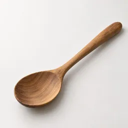 A single natural wooden spoon centered on a light neutral background.