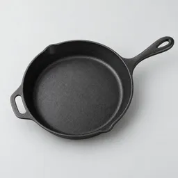 Centered studio photograph of a heavy black cast-iron skillet on a neutral light background.