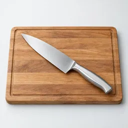 Centered studio photograph of a stainless-steel chef’s knife resting diagonally on a rectangular wooden cutting board against a light neutral background.
