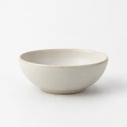 Small matte off-white ceramic bowl centered on a neutral light background.