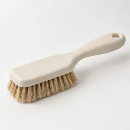 A single unbranded produce brush with a light handle and dense bristles, centered on a neutral light background.
