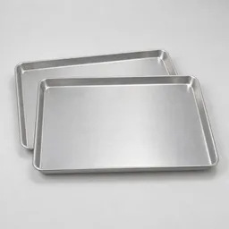 Two plain rimmed aluminum baking sheets centered on a light neutral background.