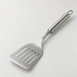 A centered stainless-steel kitchen turner with a broad slotted blade and smooth handle on a light neutral background.