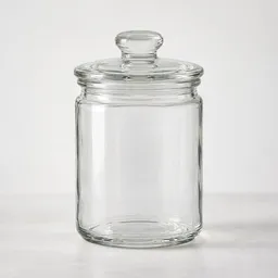 Centered clear glass jar with a fitted transparent lid on a neutral light background.