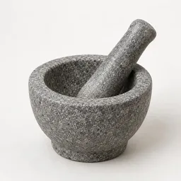 Centered stone mortar and pestle set photographed on a neutral light background.