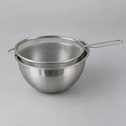 Centered stainless-steel fine-mesh strainer resting over a matching mixing bowl on a light neutral background.