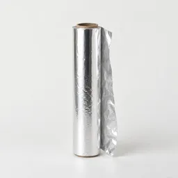 Centered unbranded roll of shiny aluminum kitchen foil on a neutral light background.